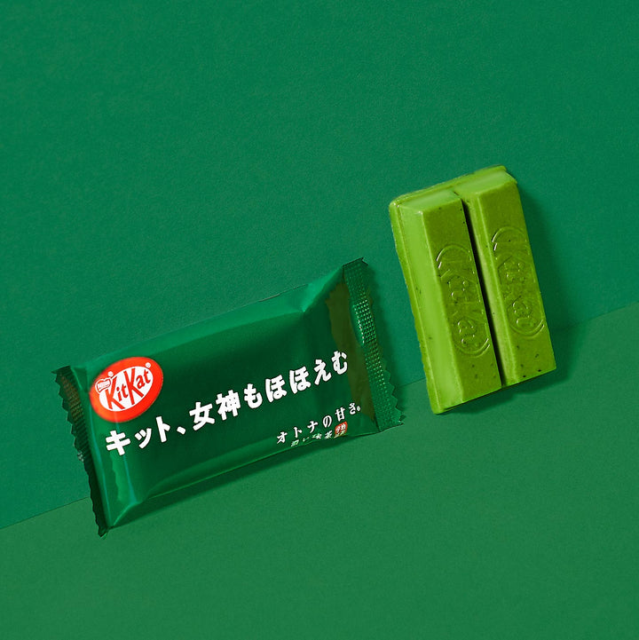 Japanese Kit Kat: Rich Green Tea bar by Nestle Japan partially unwrapped with a piece broken off, on a matching green background.