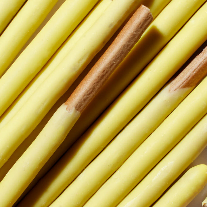 Yellow pencils arranged in parallel, with one pencil having a broken tip, resemble a variety pack of Glico Pocky: Variety Pack in their uniformity and slight variation.