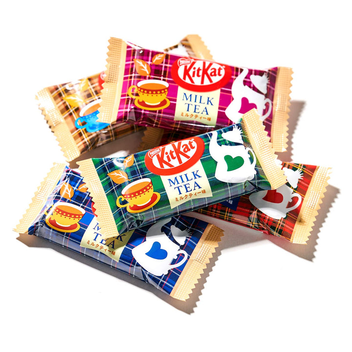 Four Nestle Japan Kit Kat bars with "Japanese Kit Kat: Milk Tea" flavor packaging, displaying vibrant colors and cup designs, arranged overlapping on a white background.