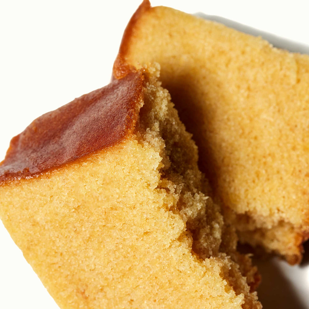 Close-up of two slices of Sakura Castella Cake on a white background with white peach.
