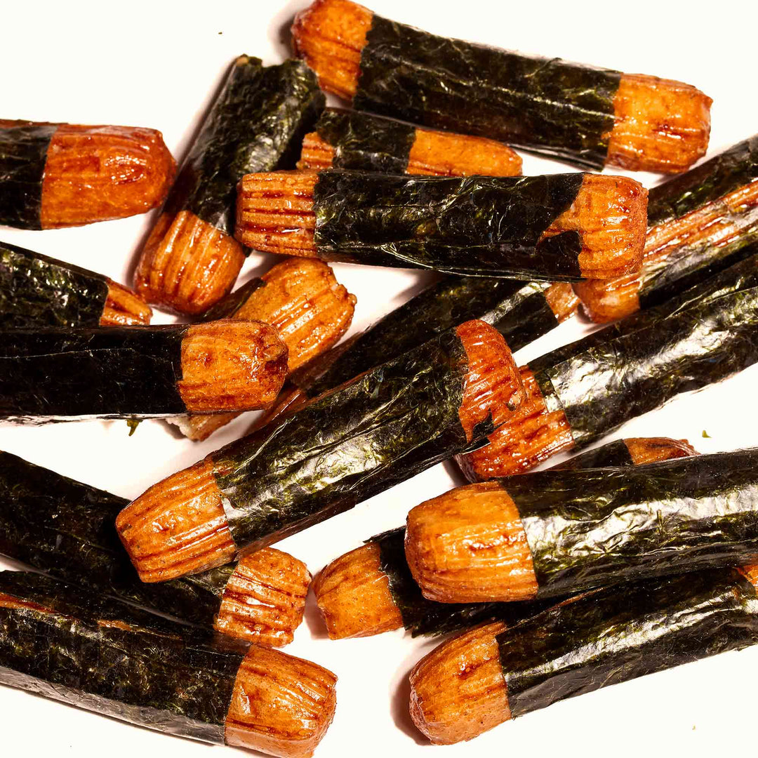 A pile of J-Basket Arare Rice Crackers: Norimaki Seaweed on a white surface.