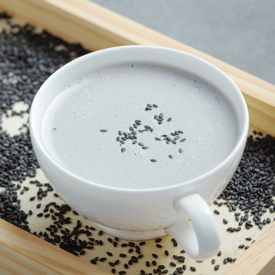 A cup of Kuki Sangyo Kuro-Goma Black Sesame Latte in a wooden tray.
