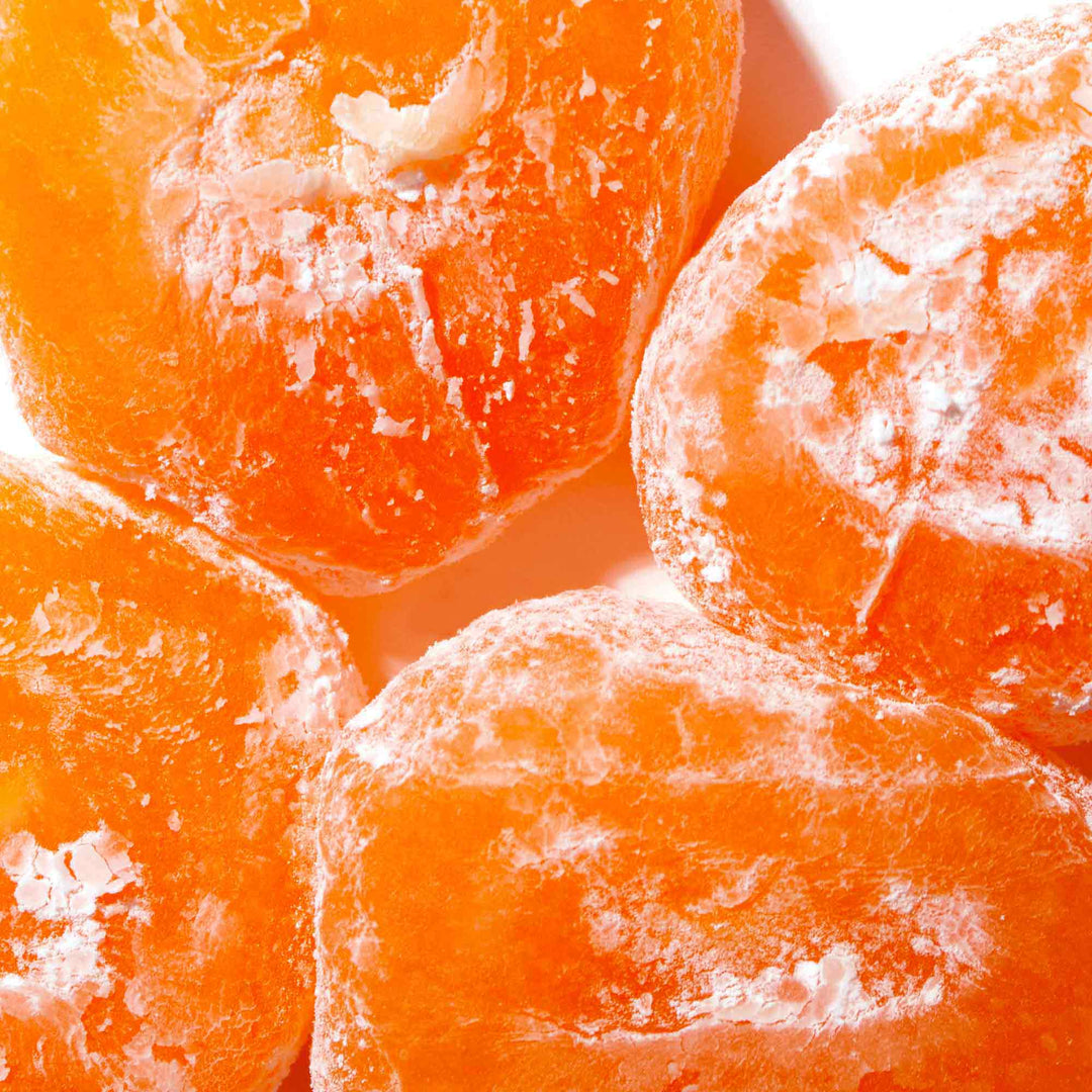Close-up of sliced, sugared apricots with visible frost particles, highlighting their vibrant orange color and juicy texture with a hint of Seiki One-Bite Mochi: Melon Choco filling.