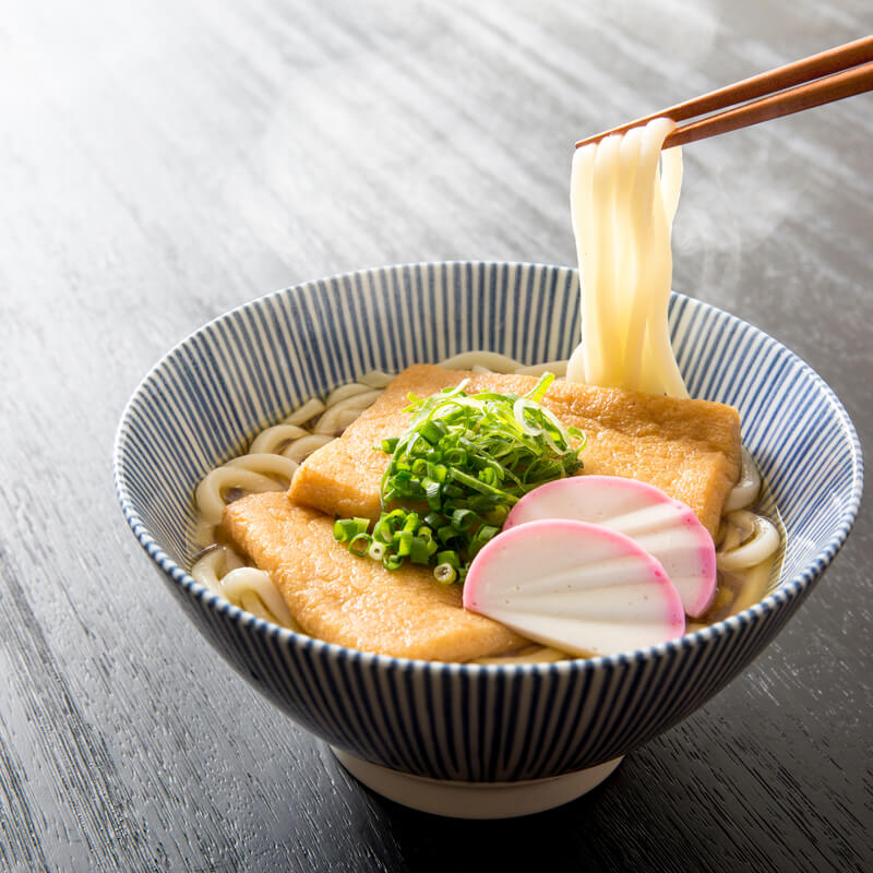 A bowl of noodle soup with Kikkoman Hon Tsuyu Soup Base and chopsticks in it.