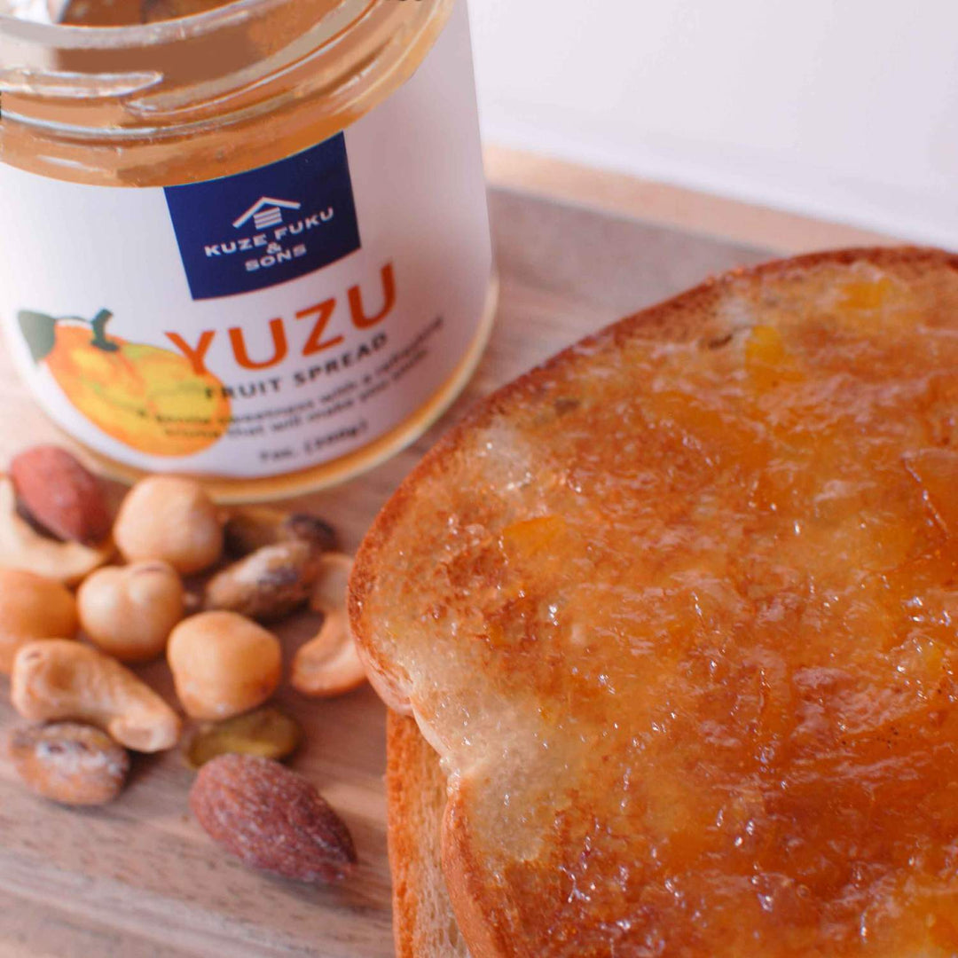A jar of Kuze Fuku Yuzu Fruit Spread and nuts on a cutting board.