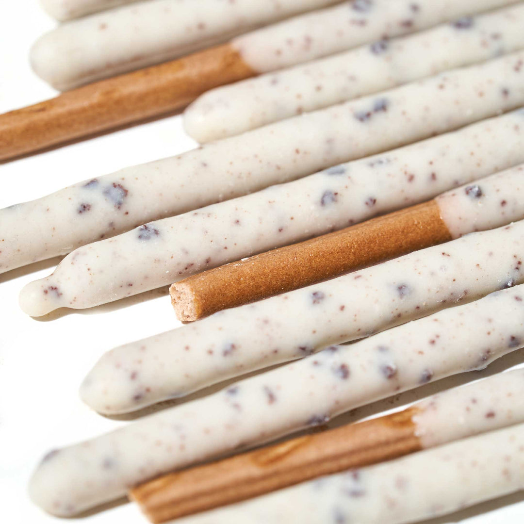 A group of Glico Pocky: Cookies & Cream sticks with white and brown sprinkles on them.