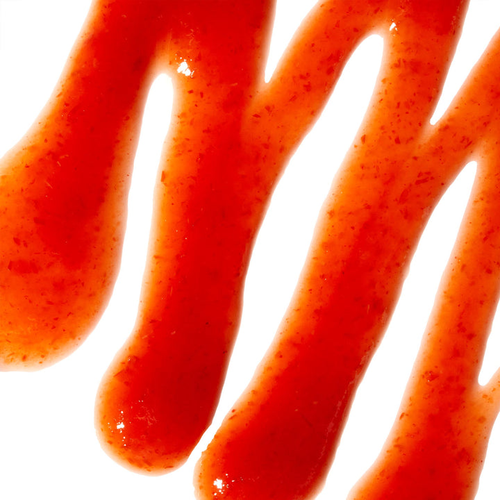 A close up of Huy Fong Sriracha Hot Chili Sauce on a white surface.