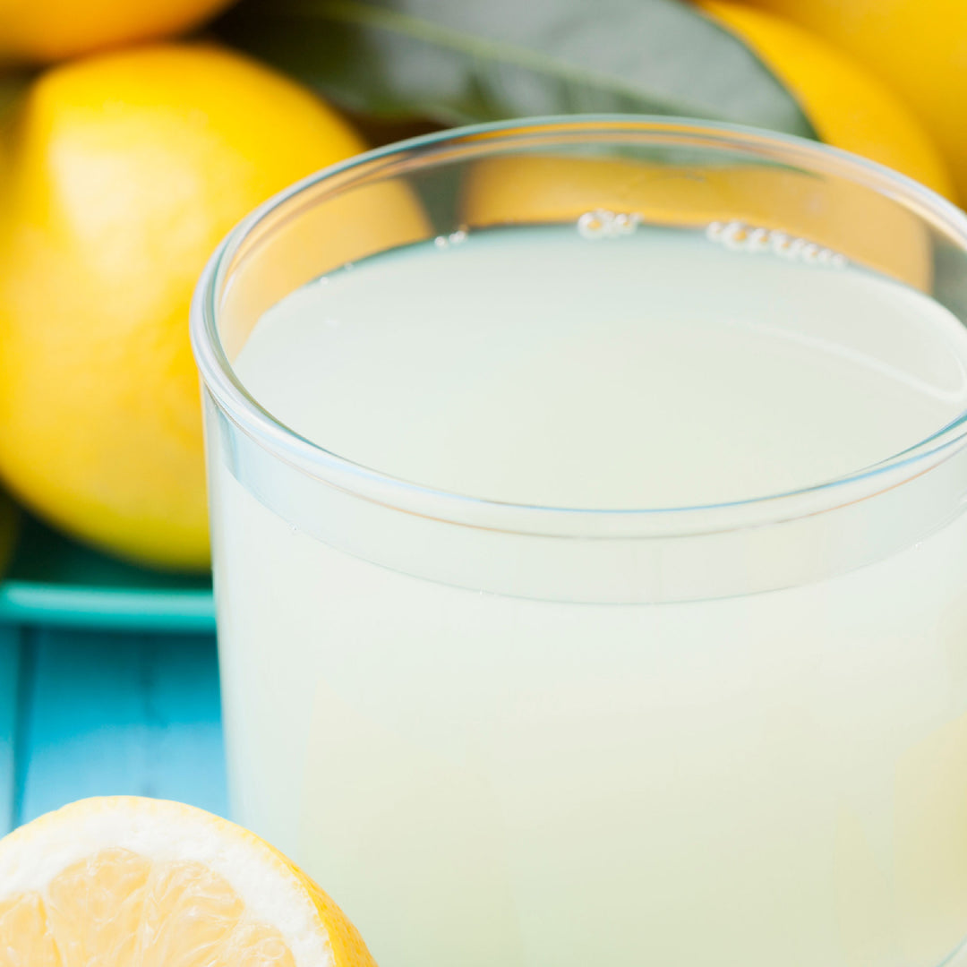 A glass of Suntory C.C. Lemon next to a bunch of lemons from Suntory.