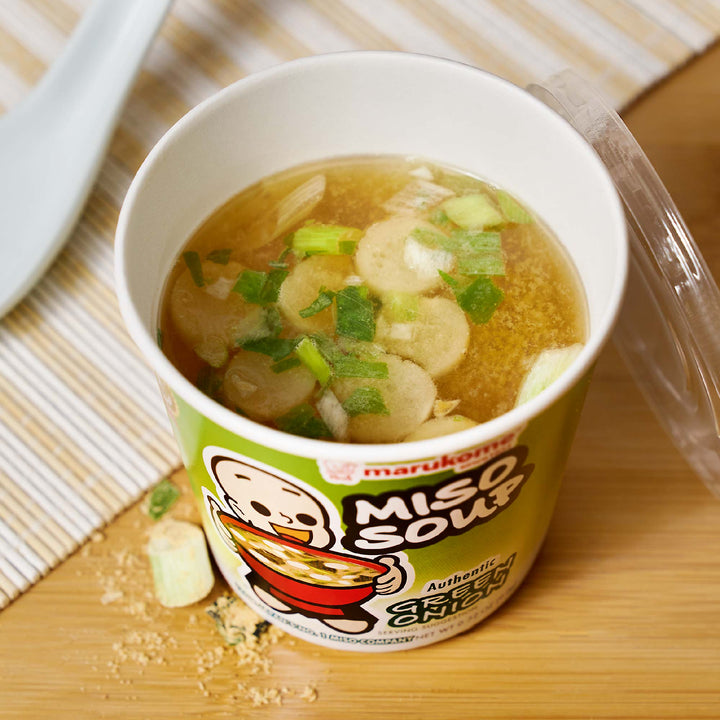 A Marukome Instant Miso Soup Cup: Green Onion sitting on a wooden table.