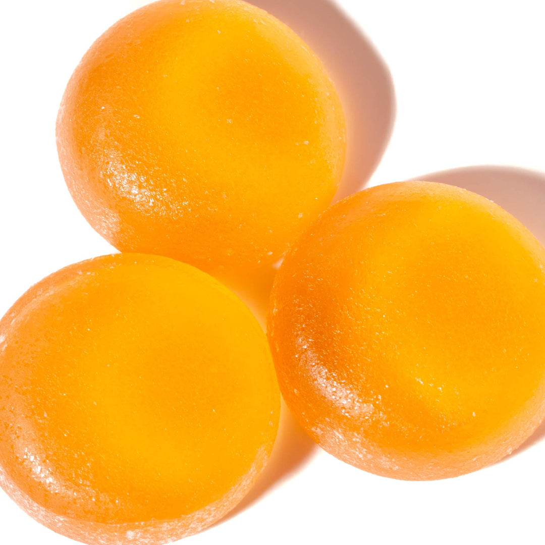 Three Kasugai Frutia Peach Gummy on a white surface.