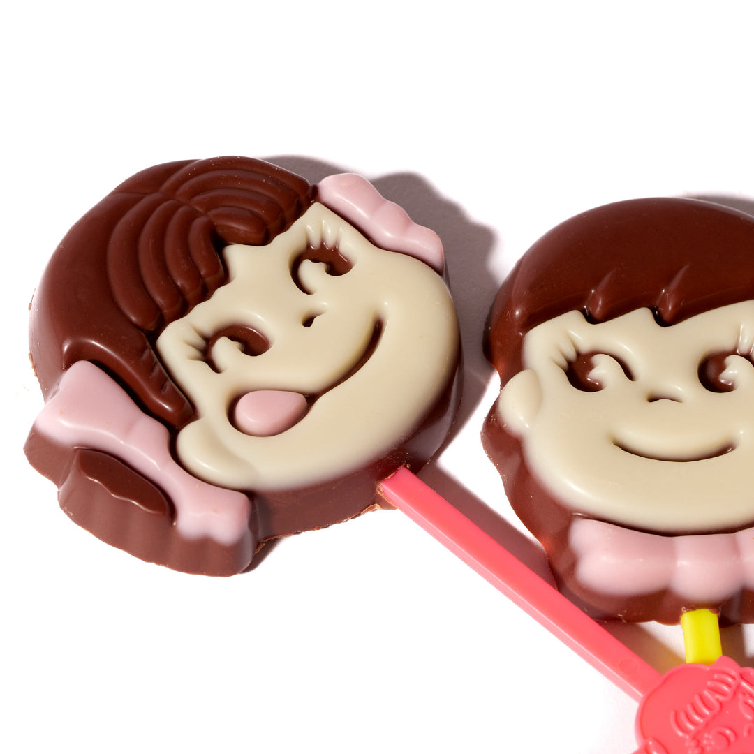 Two Fujiya Pekopoko Chocolate Lollipops with faces on them.