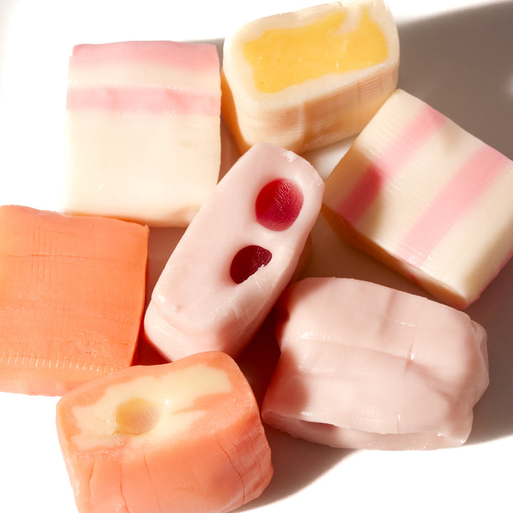 A group of UHA Mikakuto Puchao Gummy Candy: Fruit Mix in juicy flavors on a white surface.