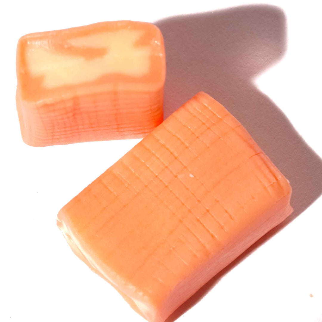 Two pieces of UHA Mikakuto Puchao Gummy Candy: Mango on a white surface.