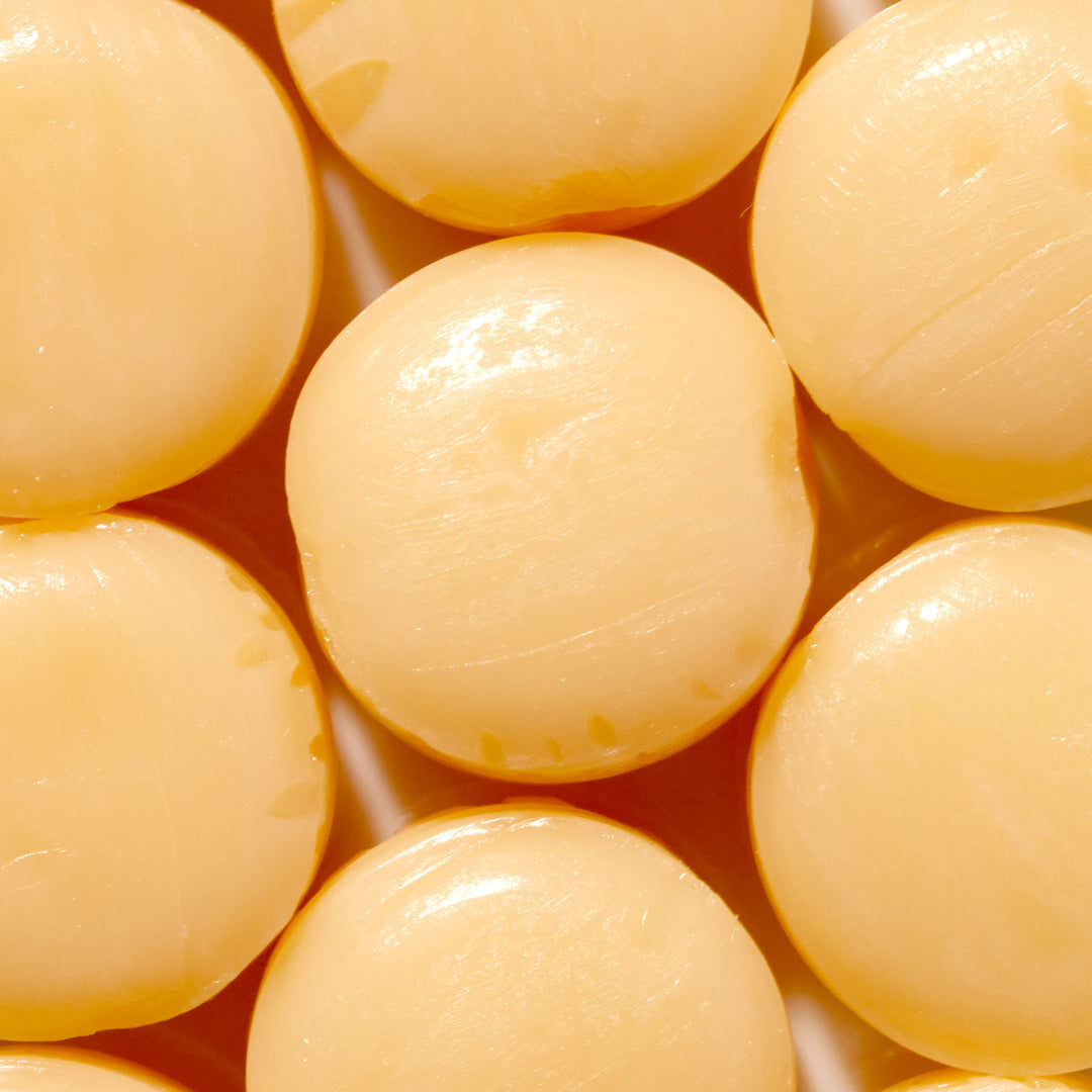 A close up of a bunch of Kasugai Peach Cream Frappe Candy yellow balls.