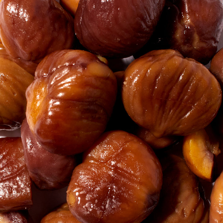 A pile of Wang Organic Roasted Peeled Chestnuts on a white surface.