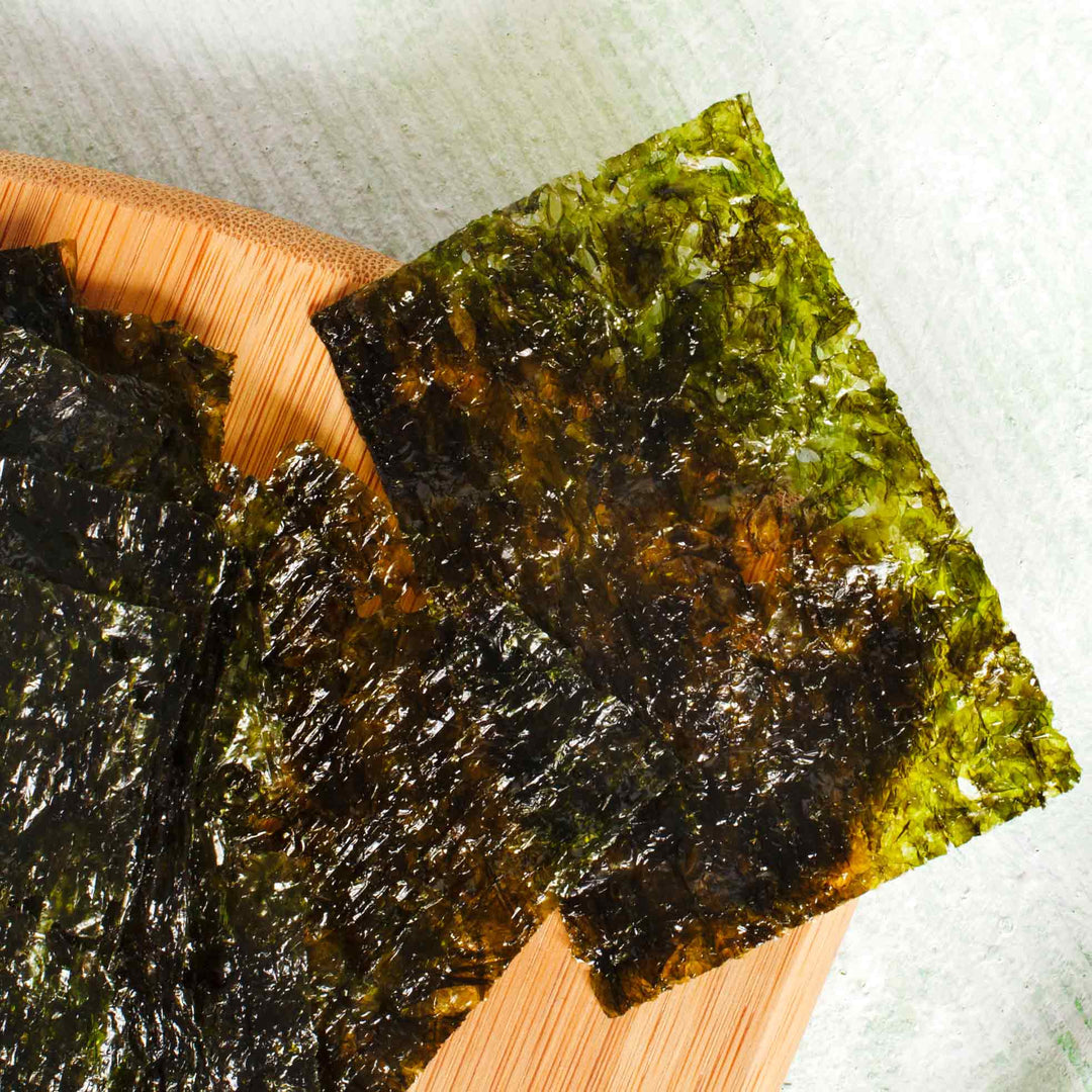 Two pieces of Wang Wasabi Seasoned Seaweed Snack (4-pack) on a wooden plate.