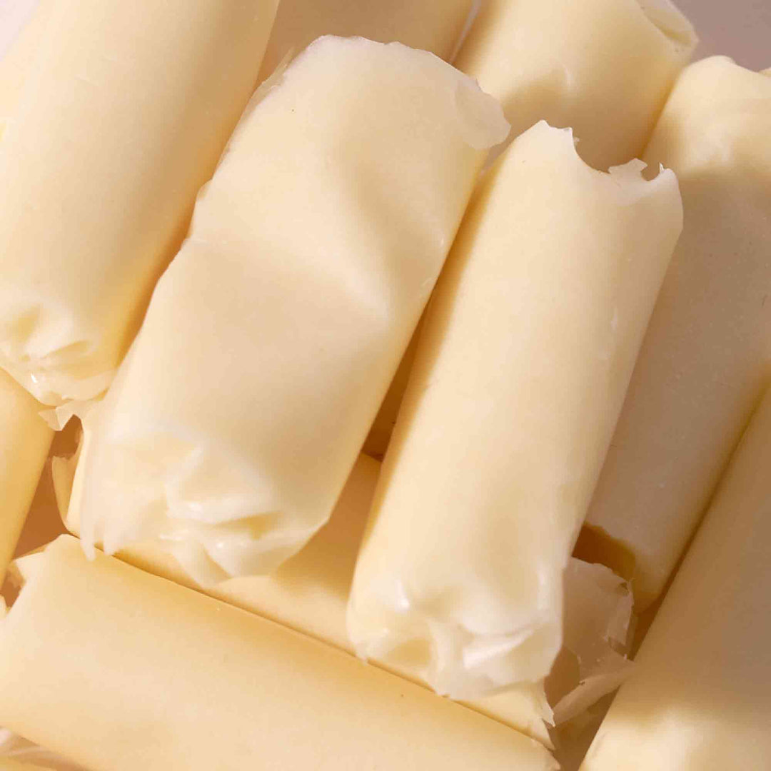 A pile of White Rabbit Creamy Candy rolls on a white surface.