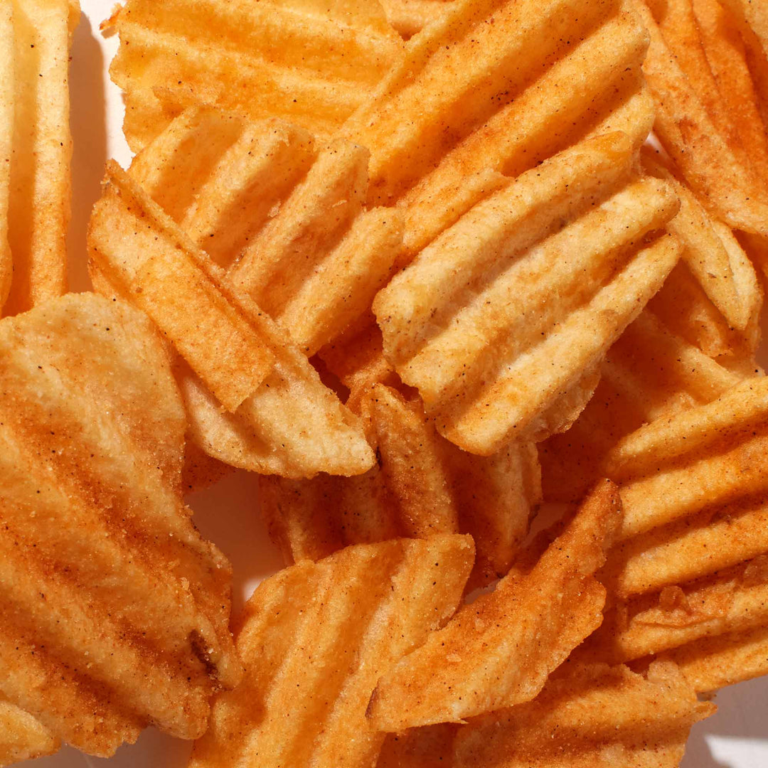 A pile of Lay's Deep Ridged Pepper Chicken potato chips on a white background.