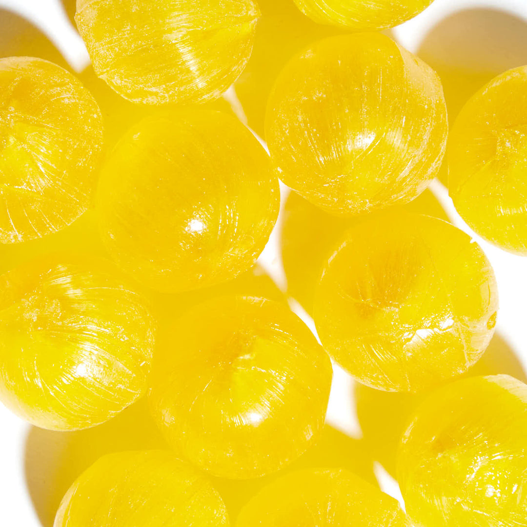 A pile of yellow Sakuma Yuzu Drops balls on a white surface.