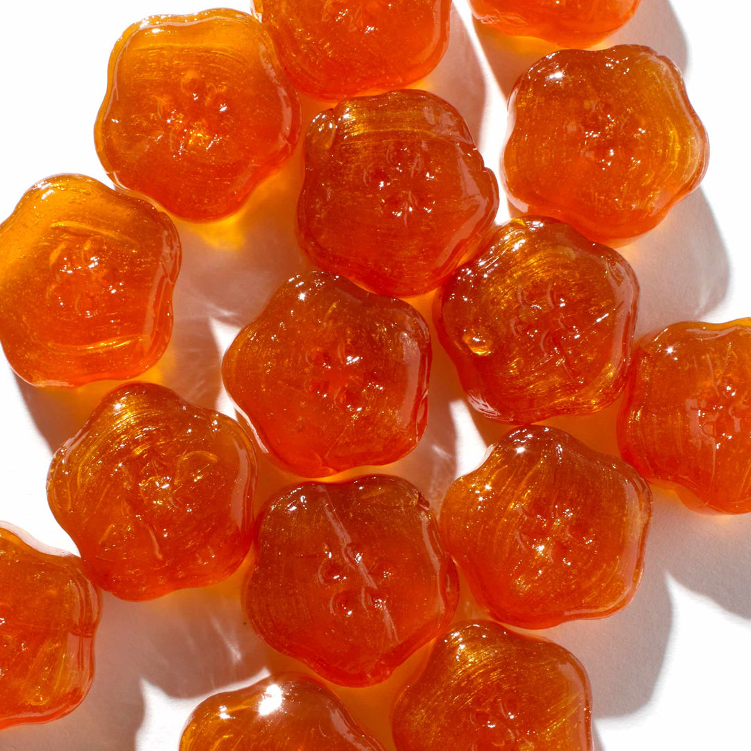 A bunch of Senjaku 100% Honey & Yuzu Candy gummy bears on a white surface.