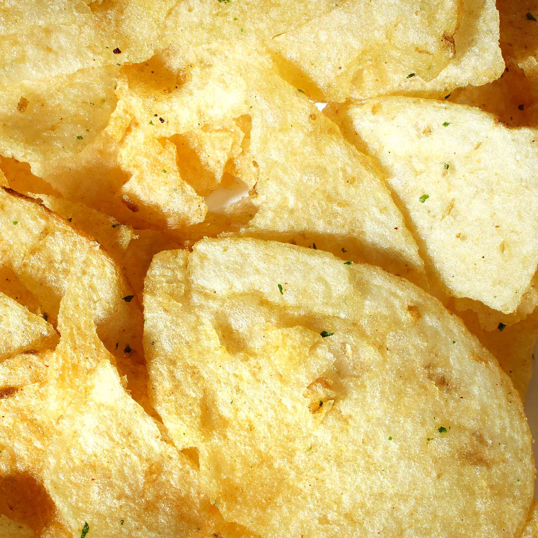 A close up of Calbee My Pote Potato Chips: Garlic Herb Butter on a white plate.