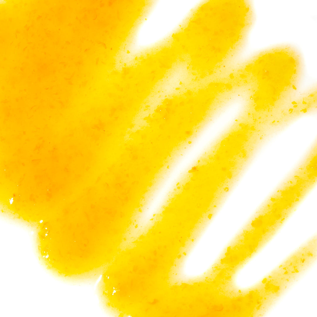 A Three Mountains Original Sriracha: Yellow liquid on a white background.