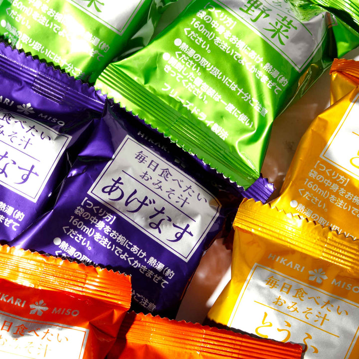 A group of individual serving packets of different kinds of snacks, including Hikari Miso Everyday Miso Soup (8 servings) from the brand Hikari.