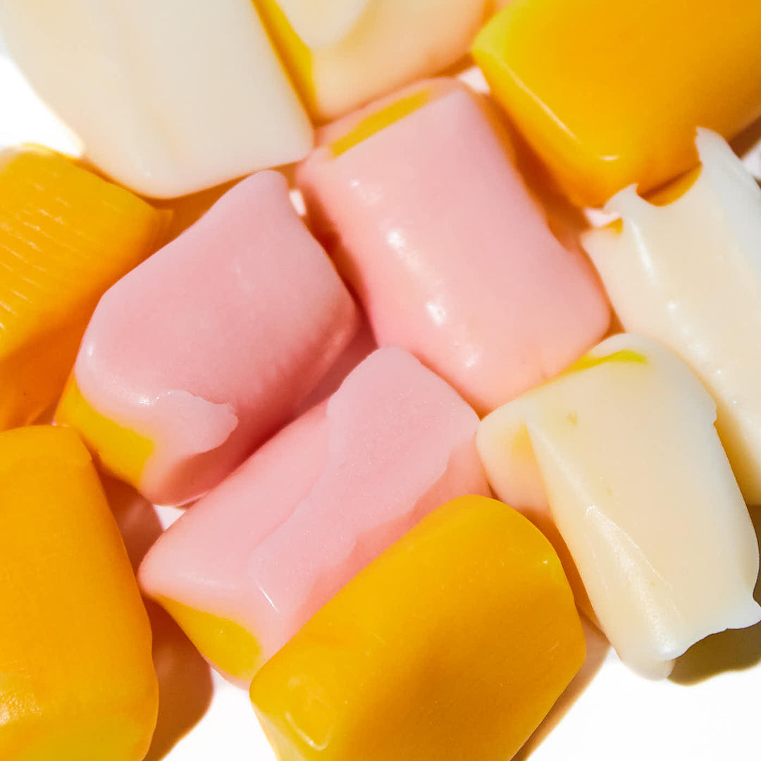A pile of Morinaga Hi-Chew: Fruit Combo Double Layered Tropical candies on a white surface.