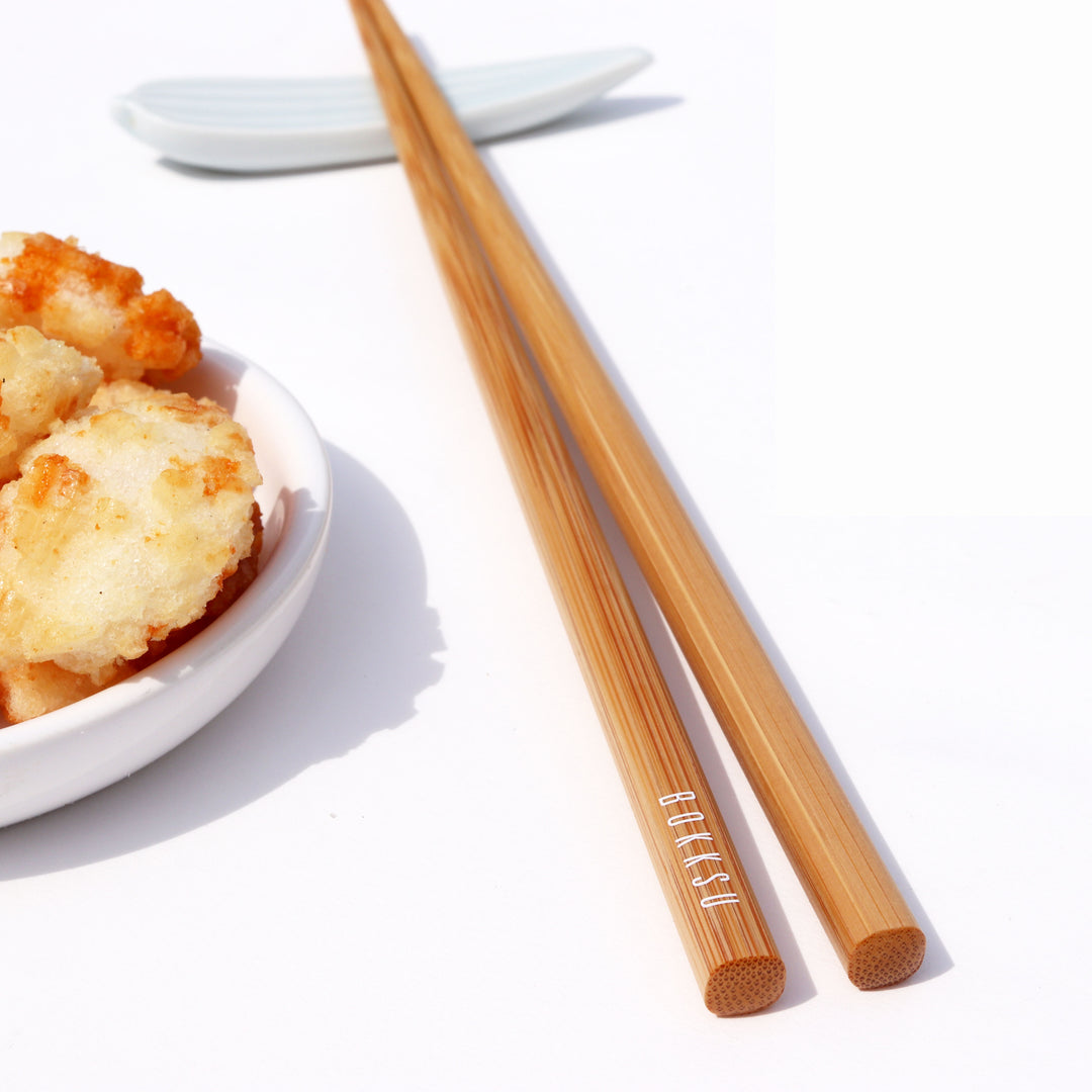 A bowl of fried rice and Bokksu Original Bamboo Chopsticks on a white table.