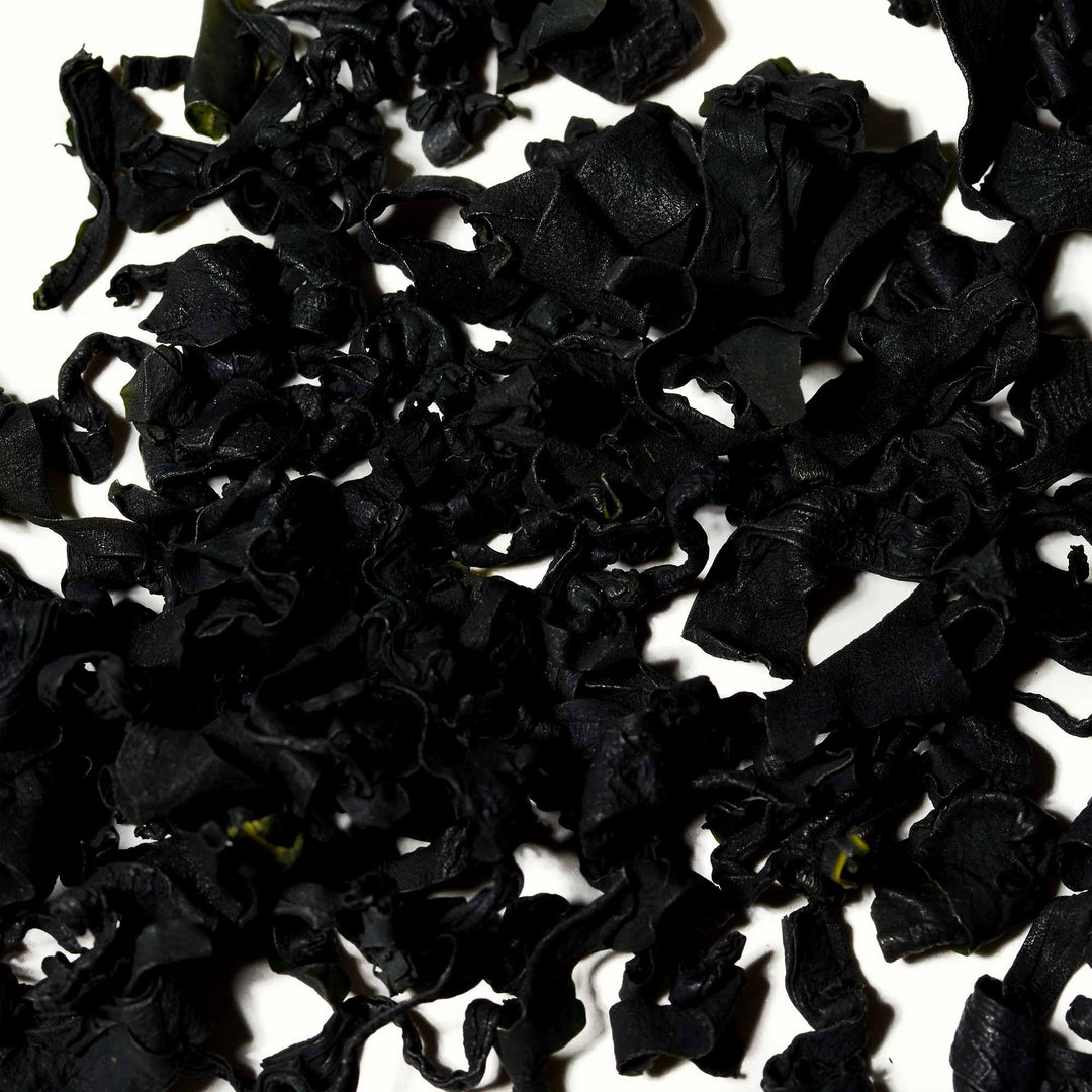 A pile of Wel-Pac Fueru Wakame Dried Seaweed on a white surface.