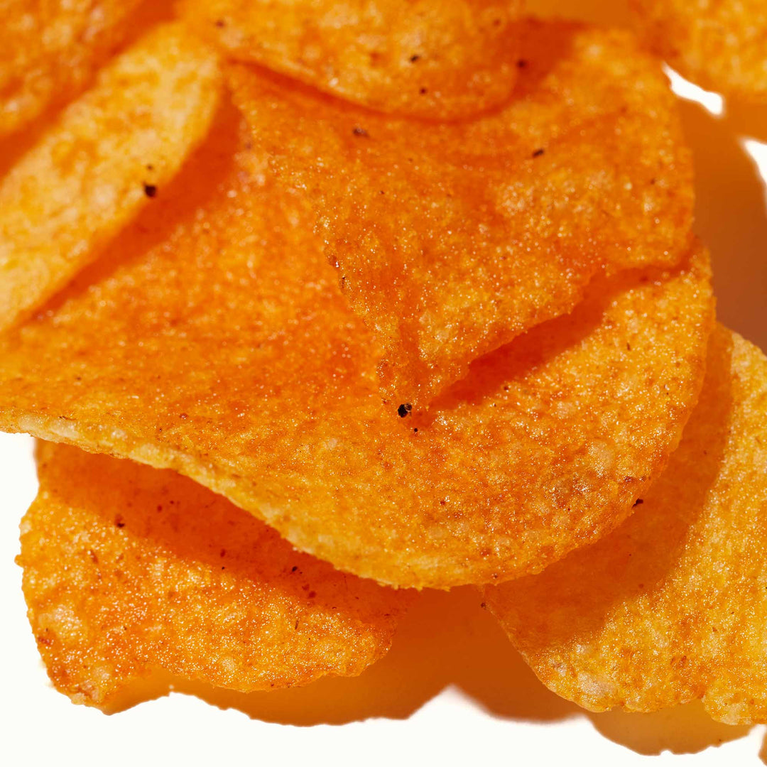 A pile of Calbee Potato Chips: Hot & Spicy on a white surface.