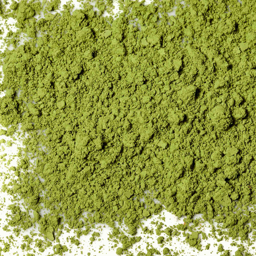 A pile of Maeda-en Matcha Green Tea Powder on a white background.