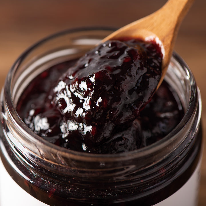 A jar of Kuze Fuku Marionberry Jam with a wooden spoon.