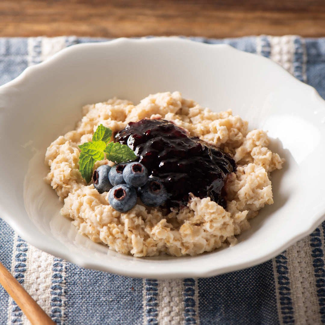 A bowl of oatmeal with Kuze Fuku Marionberry Jam and a spoon.