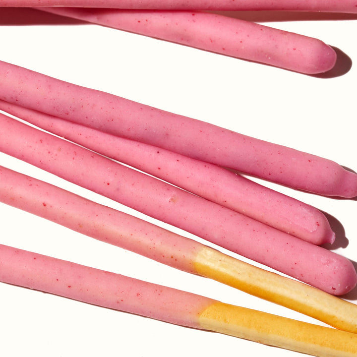 A bunch of Glico Pocky: Strawberry sticks on a white surface.