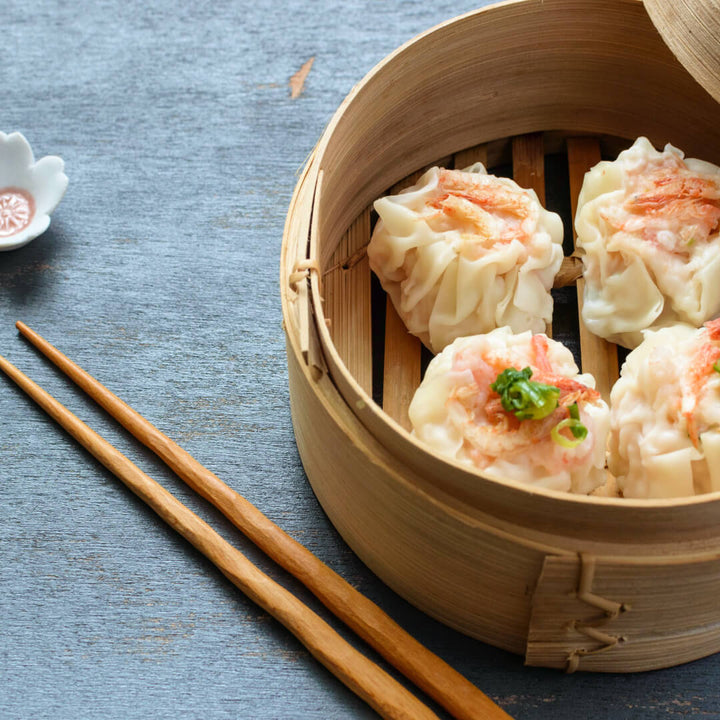 Chinese dumplings in a Premium 2-Tier Dumpling Steamer from MTC with chopsticks.