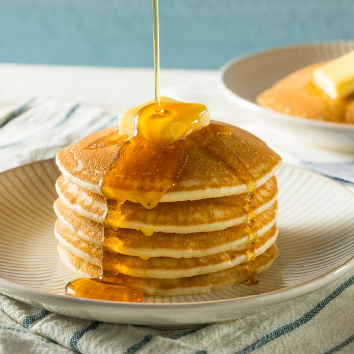 A stack of Morinaga Hotcake Mix pancakes is being drizzled with syrup.