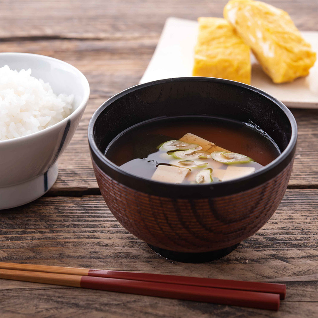 A bowl of Kuze Fuku Traditional Umami Dashi soup and a bowl of rice on a table.