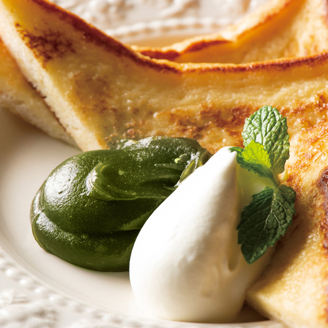 A plate of Kuze Fuku Matcha Spread french toast with sour cream and a mint leaf.