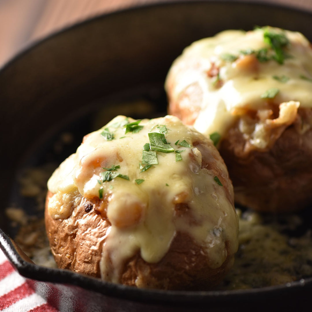 Two Kuze Fuku Garlic Miso stuffed potatoes in a skillet with cheese and parsley.