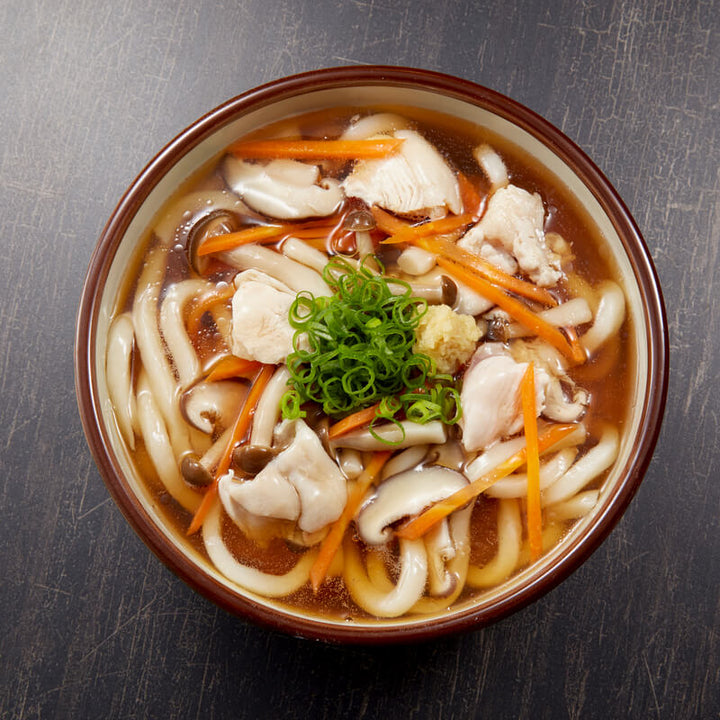 A bowl of J-Basket Katakuriko Potato Starch noodle soup with chicken and carrots.