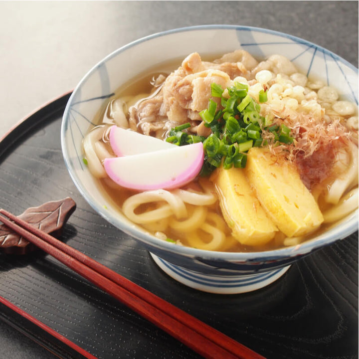 A bowl of soup with Yamahide Tenkasu Tempura Flakes and chopsticks.