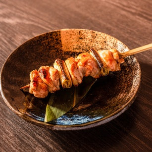 Spicy Japanese yakisoba skewers served with Ocean Foods Yuzu Kosho Pepper: Red Label on a black plate.