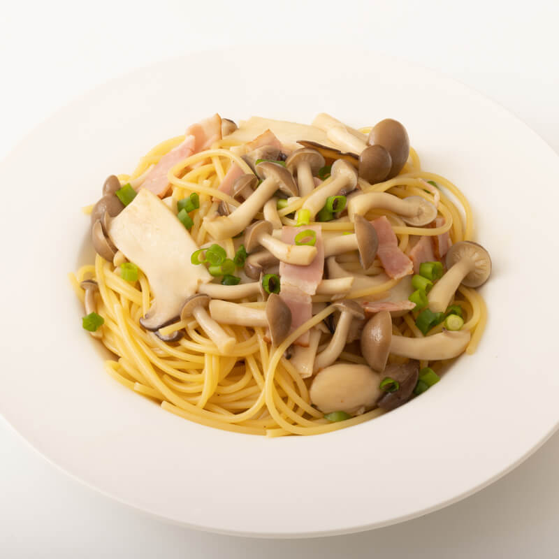 A plate of spaghetti with Kikkoman Hon Tsuyu Soup Base mushrooms and peas.